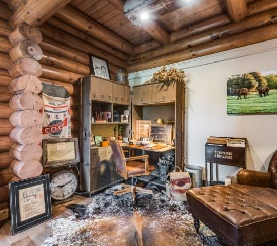 Photo of a home office built into a home with exposed round log chink style walls and exposed wood ceiling